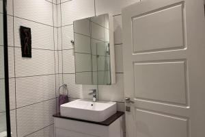 a bathroom with a sink and a mirror and a door at 3 Bed Apartment Sleeps 6 - EnSuites Parking Wifi in Freetown +20 photos