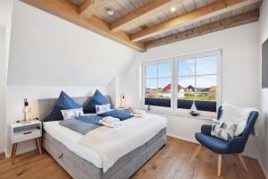 a bedroom with a large bed and a blue chair at Rügenzauber Reetdachhaus mit Sauna u Kamin Strandnähe Garten in Dranske