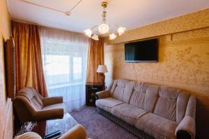 a living room with a couch and a tv at Petropavlovsk Hotel in Petropavlovsk-Kamchatskiy