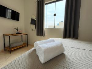 a bedroom with a white bed and a window at Hotel Carmelita in Aparecida