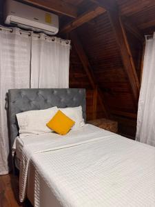 ハラバコアにあるWooden Paradise in Jarabacoaの黄色い枕が置かれたベッド