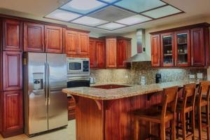 een keuken met houten kasten en een roestvrijstalen koelkast bij Beachfront, Sunset, & Ocean Views With Elevator in Tamarindo +7 foto's