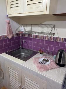 a kitchen counter with a sink and purple tiles at Ally home 14 06 in Thung Si Kan