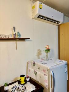 a kitchen with a washing machine with a table with flowers on it at Ally home 14 06 in Thung Si Kan