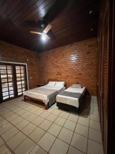 ein Schlafzimmer mit zwei Betten und einem Deckenventilator in der Unterkunft Pousada Chalé da Serra in Chapada dos Guimarães