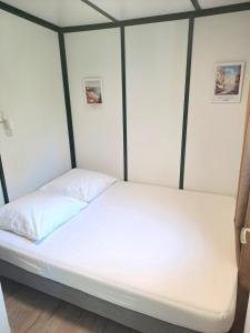 a bedroom with a bed with white sheets at Chalet Lot 23 - 4-6 places in Herm