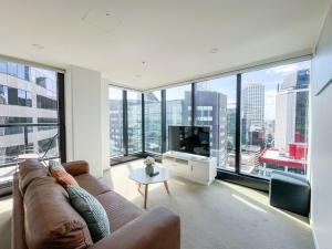 a living room with a couch and a large window at Panoramic City View High-Rise 2BR & Skytower-Adj in Auckland