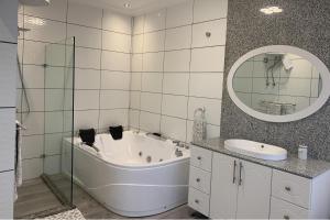 Un baño con bañera, lavabo y espejo. en 2 Bed Apartment Sleeps 4 - Jacuzzi Parking Wifi, en Freetown 23 fotos más
