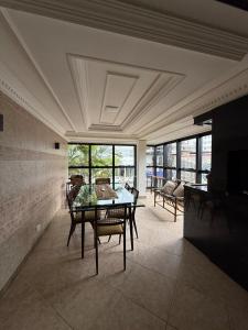 a dining room with a table and chairs and windows at Luxury, Charm and Comfort in Guaratuba in Guaratuba