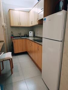 a kitchen with a white refrigerator and wooden cabinets at Amplia y Luminosa habitacion en el centro de La Laguna in La Laguna