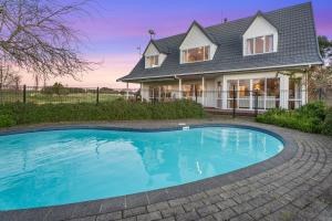 a house with a swimming pool in front of a house at The Pond House by Homello Spacious Country Retreat with Pool & Pond in Karaka