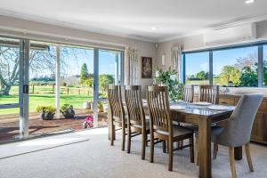 a dining room with a table and chairs and a large window at The Pond House by Homello Spacious Country Retreat with Pool & Pond in Karaka