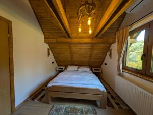 un lit dans une chambre avec un plafond en bois dans l'établissement Vila Presjenica, à Bunovci