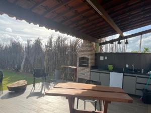 a patio with a wooden table and a kitchen at Latitude Bargada in Japaratinga