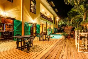 a wooden deck with tables and chairs and a pool at Monkey Room at Mahogany Hall -Gold Standard Certified in Bullet Tree Falls