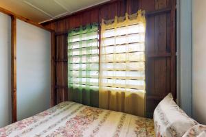 a bedroom with a bed with a window and a bedspread at Permit at Carol's Cabanas -Gold Standard Certified in Placencia Village