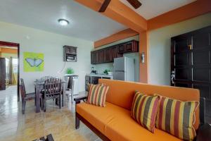 サン・ペドロにあるNew River #7 at Laguna Suite -Gold Standard Certifiedのリビングルーム(オレンジ色のソファ付)、キッチンが備わります。