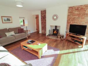 uma sala de estar com um sofá, uma televisão e uma lareira em The Old Grainstore em Wigton