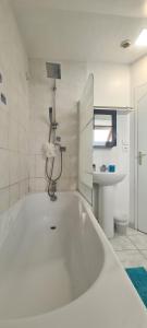 een witte badkamer met een bad en een wastafel bij Jolie maison de location avec terrasse couverte et parking privé in Douarnenez +35 foto's