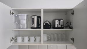 a kitchen with white shelves with coffee cups and appliances at Royal sleeping Brussels in Brussels