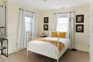 a white bedroom with a white bed with orange pillows at Urban Downtown Stamford Home 45 min to NYC with Garage And Yard in Stamford