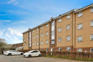 dois carros estacionados em frente a um edifício de tijolos em Stylish City Apartment with Free Parking near Town em Glasgow