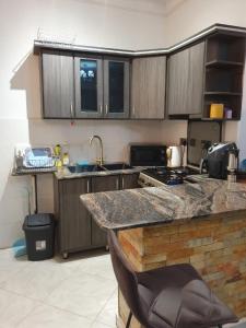 a kitchen with wooden cabinets and a counter top at Big H Apartments - 2 bedrooms - 2 bathrooms - Sittingroom - kitchen - free parking- free wifi - Fully furnished in Kitende