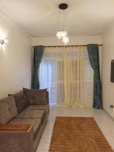 a living room with a couch and a window at Big H Apartments - 2 bedrooms - 2 bathrooms - Sittingroom - kitchen - free parking- free wifi - Fully furnished in Kitende
