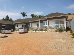 a house with cars parked in a driveway at Big H Apartments - 2 bedrooms - 2 bathrooms - Sittingroom - kitchen - free parking- free wifi - Fully furnished in Kitende