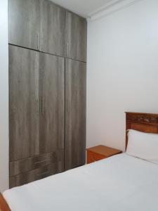 a bedroom with a bed and a wooden cabinet at Big H Apartments - 2 bedrooms - 2 bathrooms - Sittingroom - kitchen - free parking- free wifi - Fully furnished in Kitende