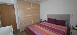 ein kleines Schlafzimmer mit einem Bett mit lila Kissen in der Unterkunft Downtown apartment - Terrace, garage and pool in Olhão