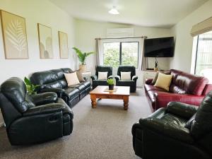 Il comprend un salon doté d'un mobilier en cuir et d'une télévision à écran plat. dans l'établissement Hosts on the Coast Tui Hills, à Aongatete