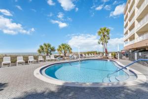 Una piscina con sillas y un edificio. en Beach View - John's Pass - Madeira Norte #208, en St Pete Beach