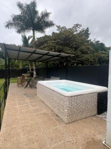 a hot tub sitting on a patio with an umbrella at Las Guias Cabaña Privada in Río Hato