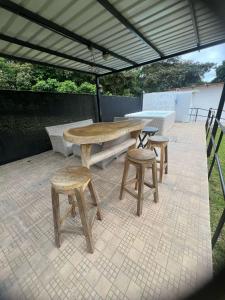 a picnic table and two stools under a canopy at Las Guias Cabaña Privada in Río Hato