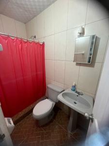 a bathroom with a toilet and a sink and red shower curtain at Las Guias Cabaña Privada in Río Hato