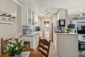 a kitchen with white cabinets and a table and chairs at Beautiful 1 Bed Beach Condo #122 in Carpinteria