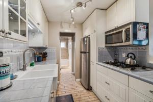 a kitchen with white cabinets and a sink and a microwave at Beautiful 1 Bed Beach Condo #122 in Carpinteria