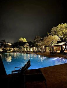a large swimming pool with blue water at night at Studio lindíssimo Vila do Lago- 900m da vila in Praia do Forte