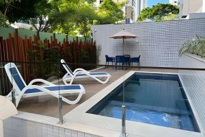 - une piscine avec des chaises, une table et un parasol dans l'établissement Bnb Flex Suites, à Récife