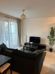 ein Wohnzimmer mit einer schwarzen Couch und einem Tisch in der Unterkunft Chic 2 chambres appartement proche de Paris in Vitry-sur-Seine