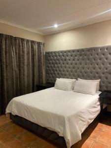 a bedroom with a large bed with a large headboard at Castle Ridgeview guesthouse in Pretoria +4 photos