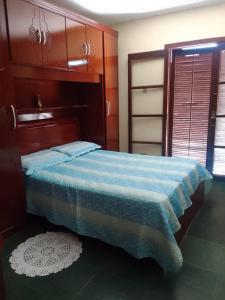 ein Schlafzimmer mit einem Bett mit einer blauen Decke in der Unterkunft Casa no Condomínio Moana - Praia Martins de Sá in Caraguatatuba