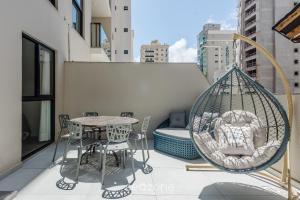 a balcony with a table and chairs and a swing at Sua estadia exclusiva a poucos passos do Mar em Meia Praia - FFS in Perequê