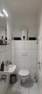 a white bathroom with a toilet and a sink at Skyline-Aussicht und fantastische Sonnenuntergänge in Langen