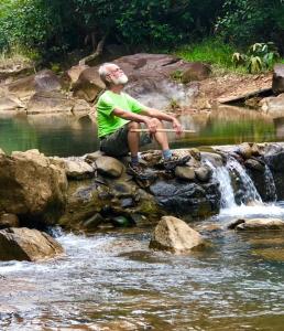 Un hombre sentado en las rocas junto a una cascada. en The Nest Rainforest Retreat, en Panamá 10 fotos más