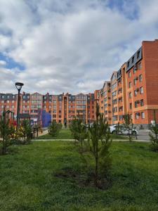 a park in front of a large brick building at Уютная новая квартира в ЖК Береке 2 рядом с Kostanay Plaza in Kostanay +36 photos