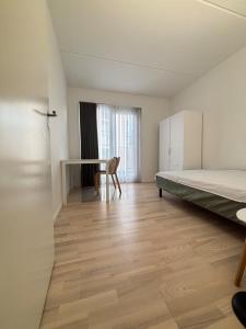 une chambre vide avec un lit et un bureau dans l'établissement Cozy Townhouse near Copenhagen, à Rødovre