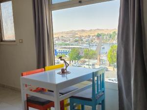 Una mesa y sillas en una habitación con ventana. en Pajama Hostel Nile View, en Asuán