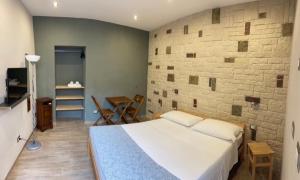 une chambre avec un grand lit et un mur de briques dans l'établissement Annette Rooms, à Bari